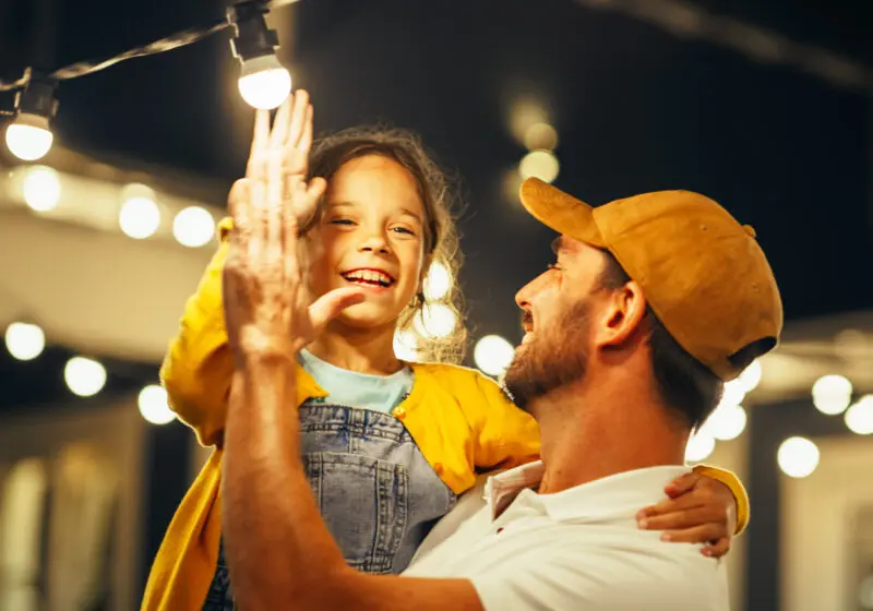 man holding daughter under lights at night