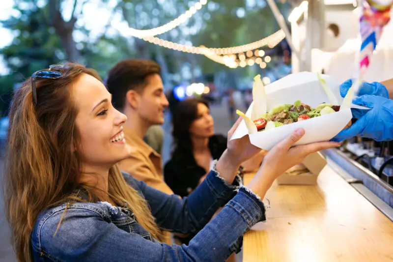 Group of attractive young friends buying food from a gourmet food truck.