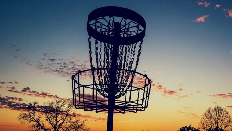 close up of disc golf target basket at sunset