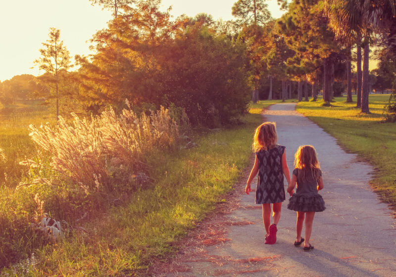 two girls walking by lake holding hands